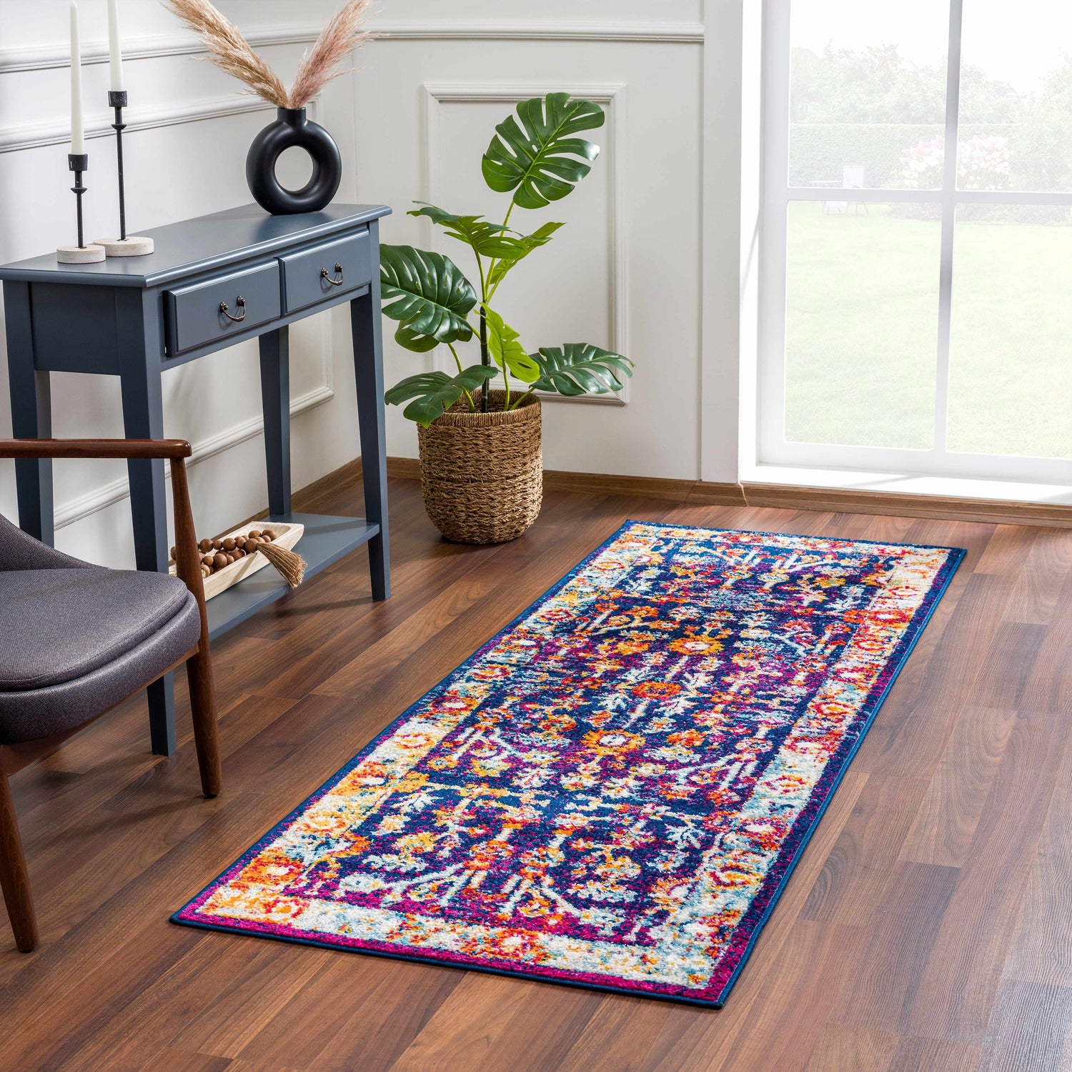 Entryway with Istanbul Vintage Navy Area Rug, blue console table, monstera plant, and wood floors. Roomscene-Runner