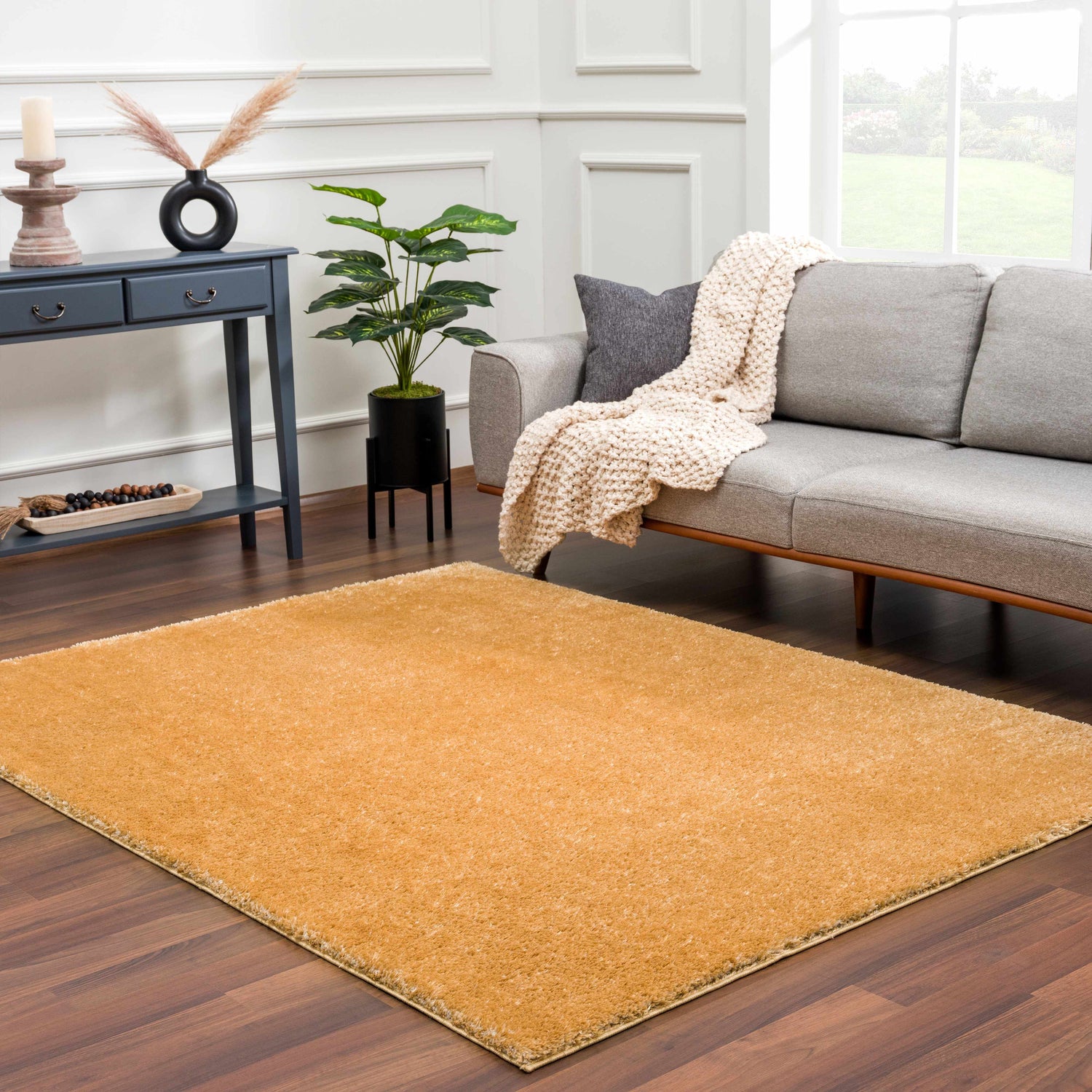 Living room scene with gray sofa and the Heavenly Solid Mustard Plush Rug on dark wood floors. Roomscene-Rectangle