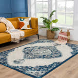 Living room scene with a Bohemian Istanbul Blue Area Rug, mustard sofa, and blue accent wall. Roomscene-Rectangle