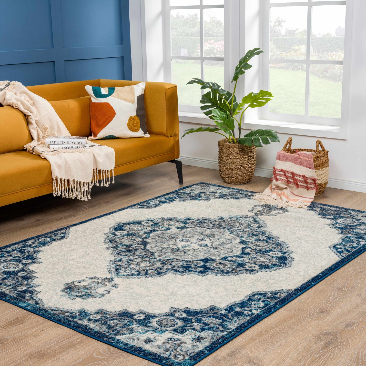 Living room scene with a Bohemian Istanbul Blue Area Rug, mustard sofa, and blue accent wall. Roomscene-Rectangle