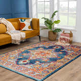 Living room scene with Istanbul Medallion Blue & Orange rug, mustard sofa, and blue accent wall. Bright, bohemian style. Roomscene-Rectangle