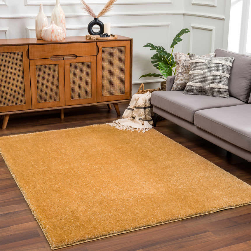 Living room scene with a Heavenly Solid Mustard Plush Rug, gray sofa, and wooden cabinet. Roomscene-Rectangle