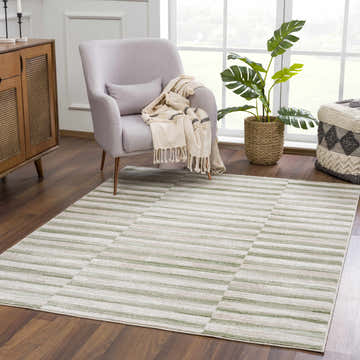 Living room scene with a Liverpool Broken-Striped Area Rug in ivory, off-white, and olive. Modern armchair and wood cabinet. Roomscene-Rectangle