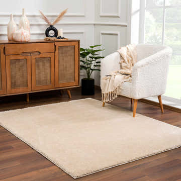 Living room scene with a Heavenly Dark Beige Area Rug, wood cabinet, and cozy white chair. Roomscene-Rectangle
