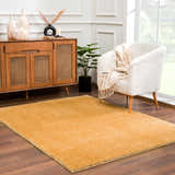 Living room scene with a Heavenly Solid Mustard Plush Rug, white chair, and wood cabinet. Roomscene-Rectangle