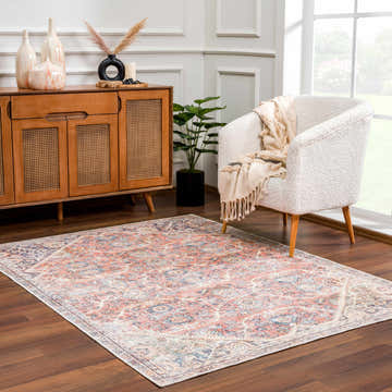 Living room scene with Konstantina Washable Area Rug in peach, blue, and beige. Features a vintage Persian design and wood accents. Roomscene-Rectangle