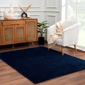 Living room scene with a Navero Dark Blue rug, wood cabinet, and white chair. Roomscene-Rectangle