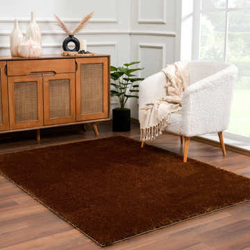 Living room scene with a Heavenly Solid Brown Plush Rug, wood cabinet, and white armchair. Roomscene-Rectangle