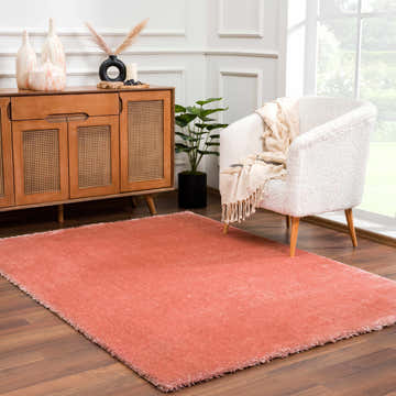 Living room scene with Rosava Dusty Pink rug, wood cabinet, white chair, and natural light from a window. Roomscene-Rectangle
