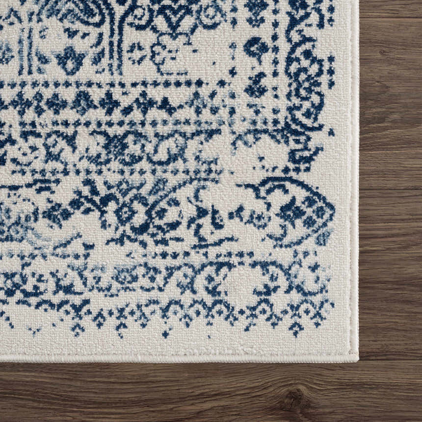 Close-up of the Michie Blue Area Rug showing its dark blue, light blue, and white bohemian pattern and machine woven texture. Swatch