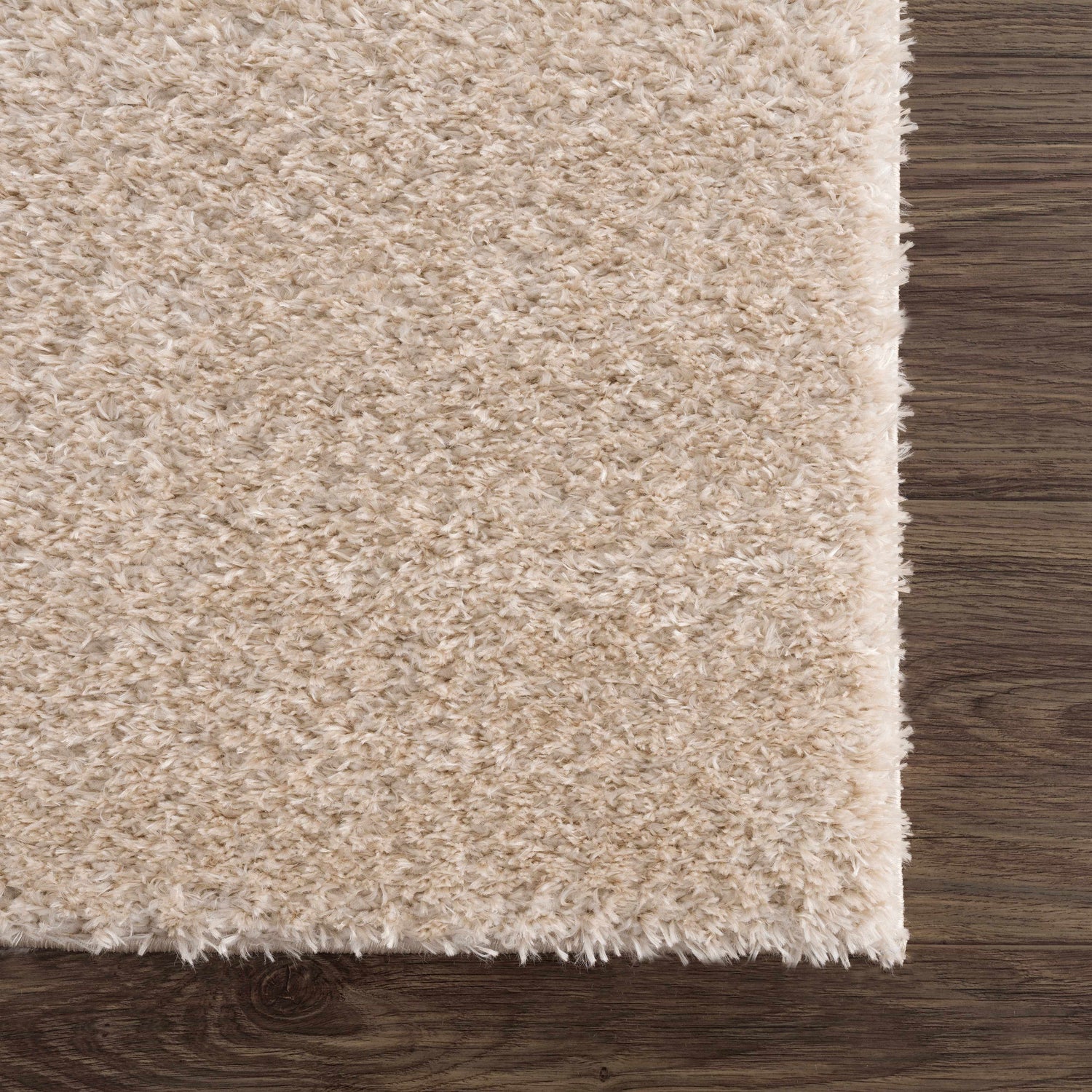 Close up of the Heavenly Dark Beige Area Rug showing its shag texture and color against a dark wood floor. Swatch