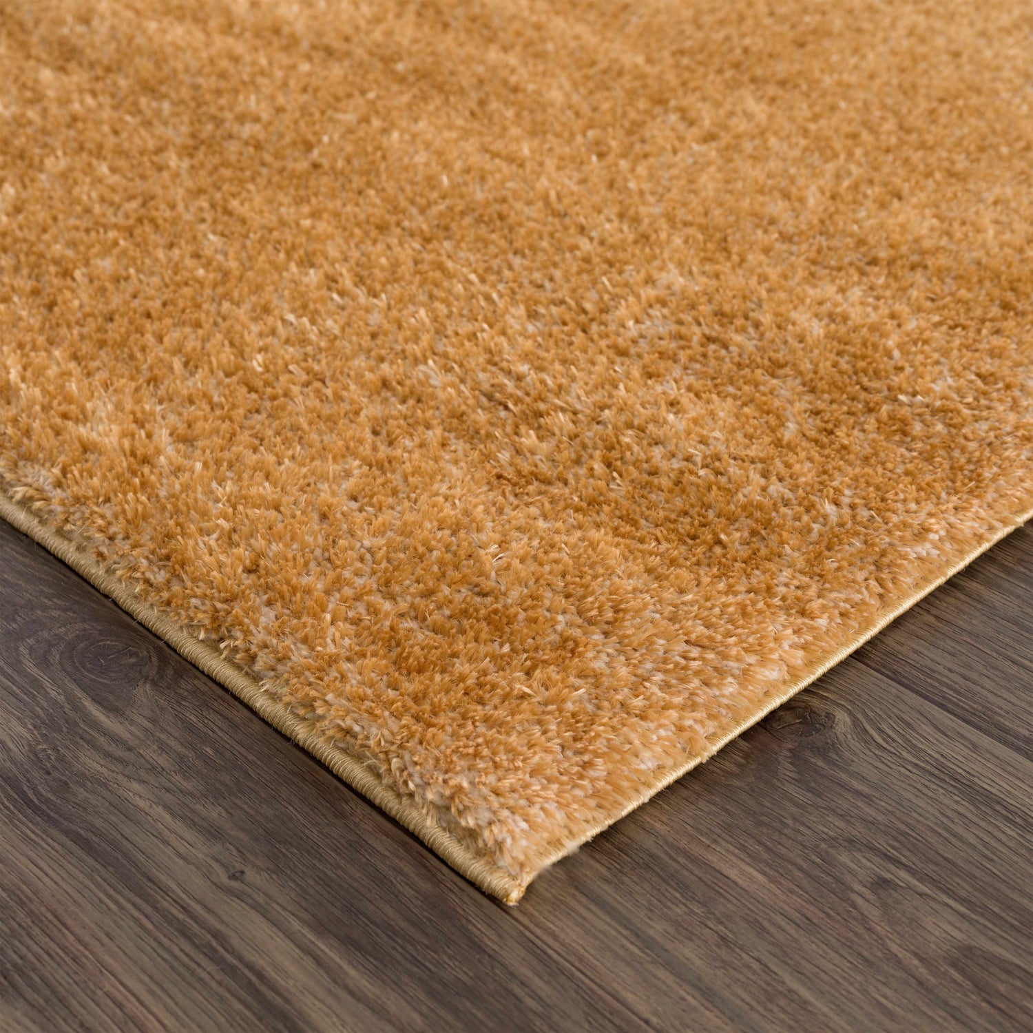 Close-up of a Heavenly Solid Mustard Plush Rug showing its soft texture and color on dark wood flooring. Corner