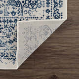 Close-up of Michie Blue Area Rug showing its dark blue, light blue, and white bohemian pattern and machine woven construction. Fold