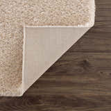 Close-up of Heavenly Dark Beige Area Rug showing its shag texture and backing on dark wood floors. Fold