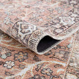 Close-up of a Bian Washable Area Rug. Features a vintage Persian design in aqua, beige, and rose cream hues. Fold