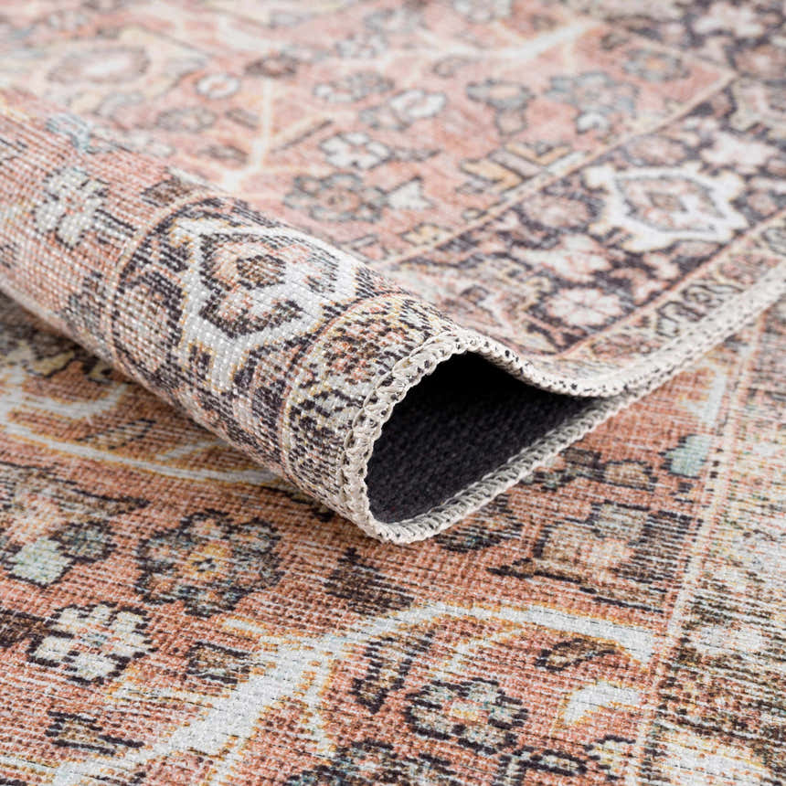 Close-up of a Bian Washable Area Rug. Features a vintage Persian design in aqua, beige, and rose cream hues. Fold