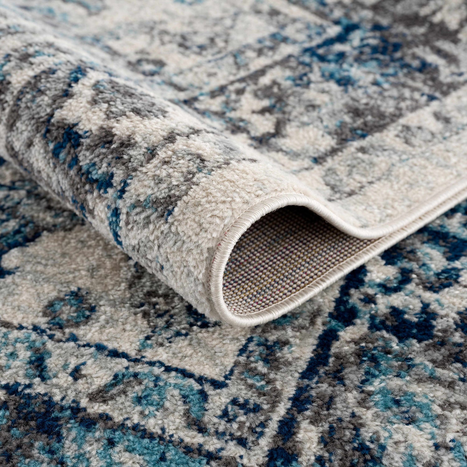 Close-up of the Istanbul Vintage Blue Area Rug showing its ivory, navy, and gray traditional pattern. Fold