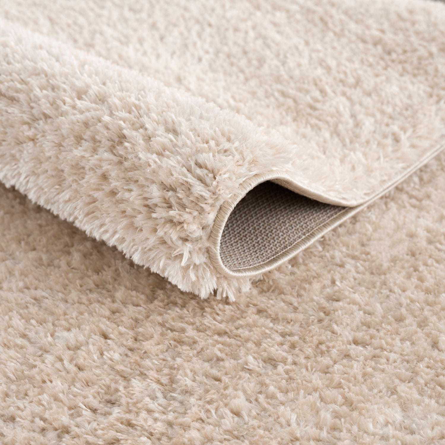 Close-up of the Heavenly Dark Beige Area Rug showing its shag texture and neutral color. Fold