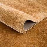 Close-up of the Heavenly Solid Mustard Plush Rug showing its soft, shag texture and bound edge. Fold
