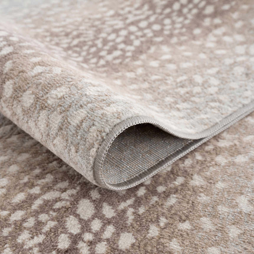 Close-up of the Pointblank Tan Leopard Print Rug showing the tan and ivory animal print pattern and machine-woven texture. Fold