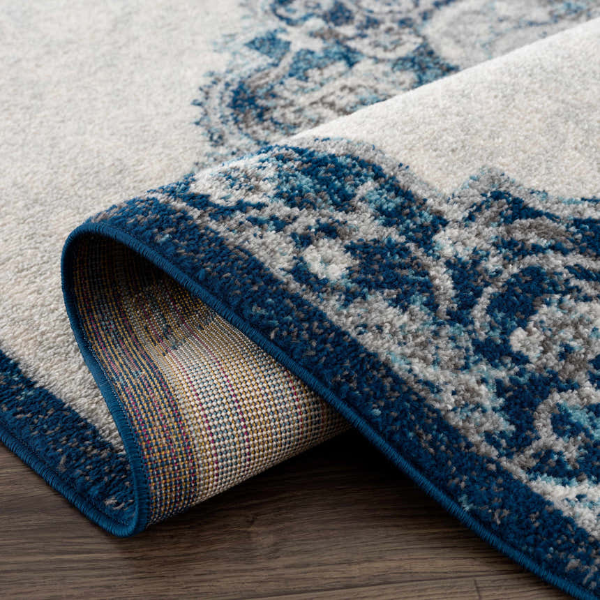 Close-up of the Istanbul Blue Area Rug showing the ivory and navy Persian-style pattern and the rug's construction. Fold
