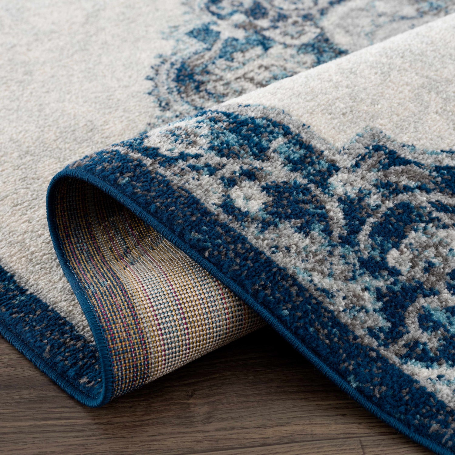 Close-up of the Istanbul Blue Area Rug showing the ivory and navy Persian-style pattern and the rug's construction. Fold