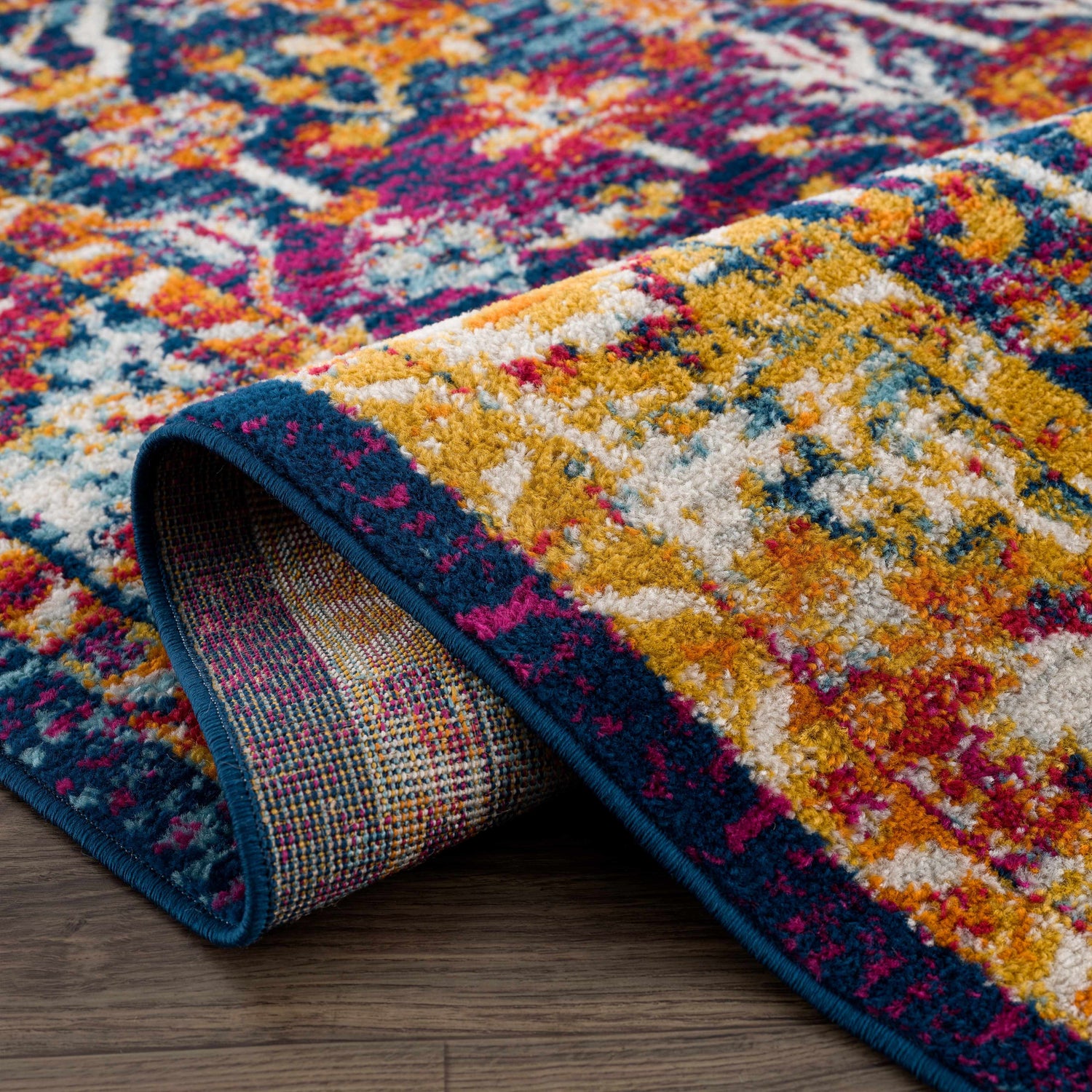 Close-up of the Istanbul Vintage Navy Area Rug showing its navy, ivory, yellow, and pink bohemian pattern. Fold