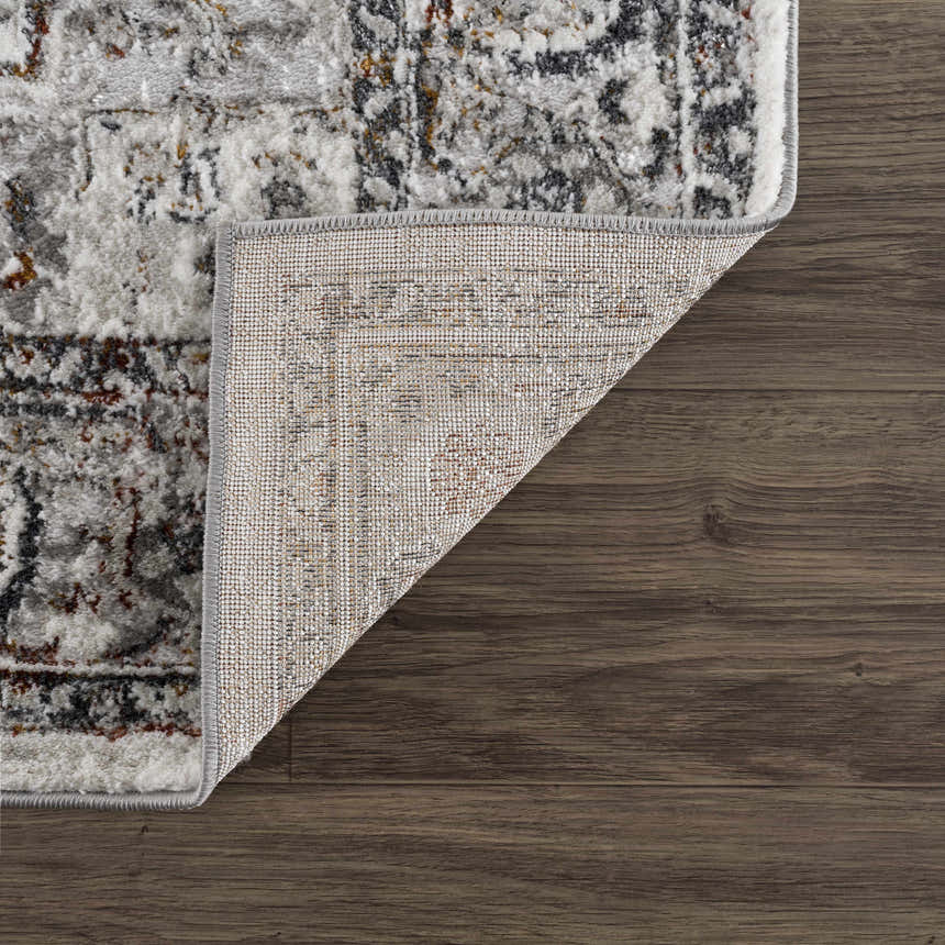 Close-up of the Liverpool Dark Gray Area Rug showing its charcoal, gray, rust colors, traditional pattern, and machine-woven construction. Fold