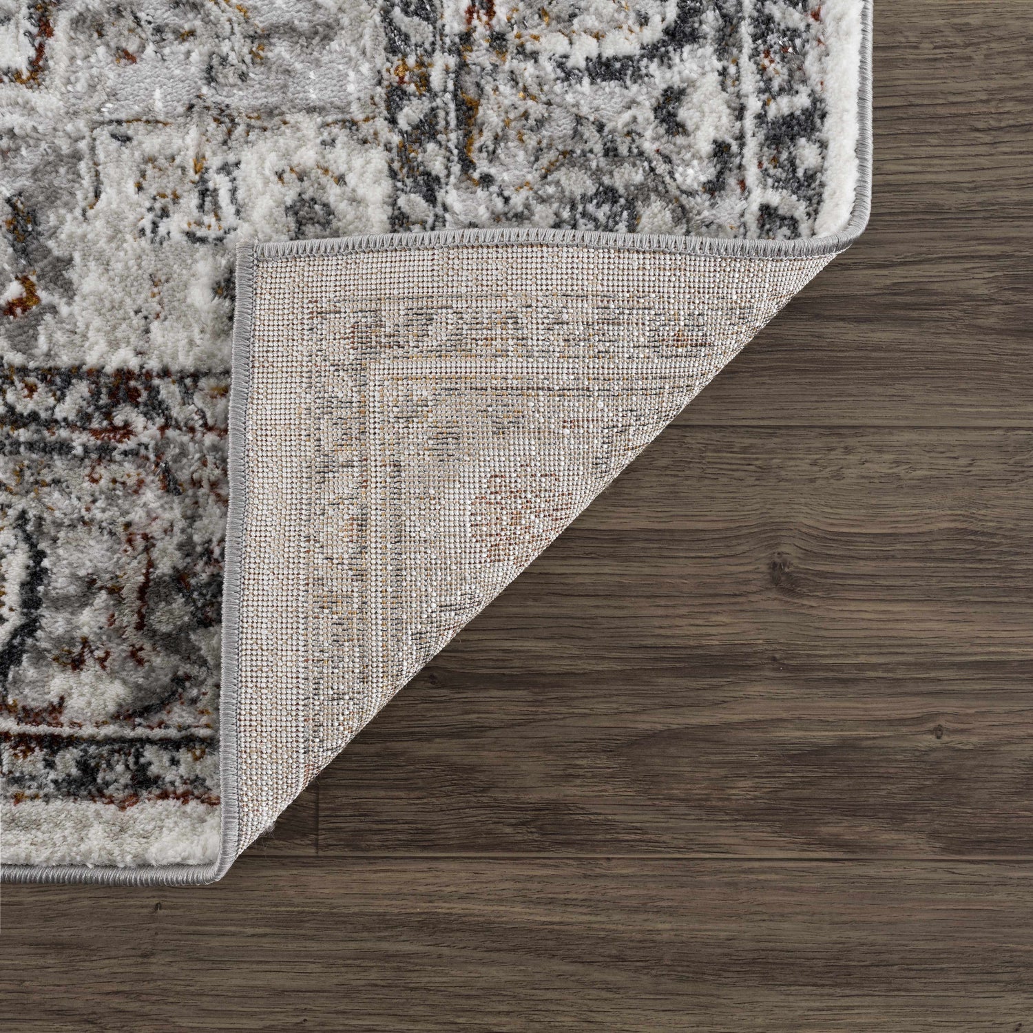 Close-up of the Liverpool Dark Gray Area Rug showing its charcoal, gray, rust colors, traditional pattern, and machine-woven construction. Fold