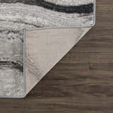 Close-up of Live Marble Dark Gray Area Rug showing charcoal, gray, and rust hues on wood floor with rug backing. Fold