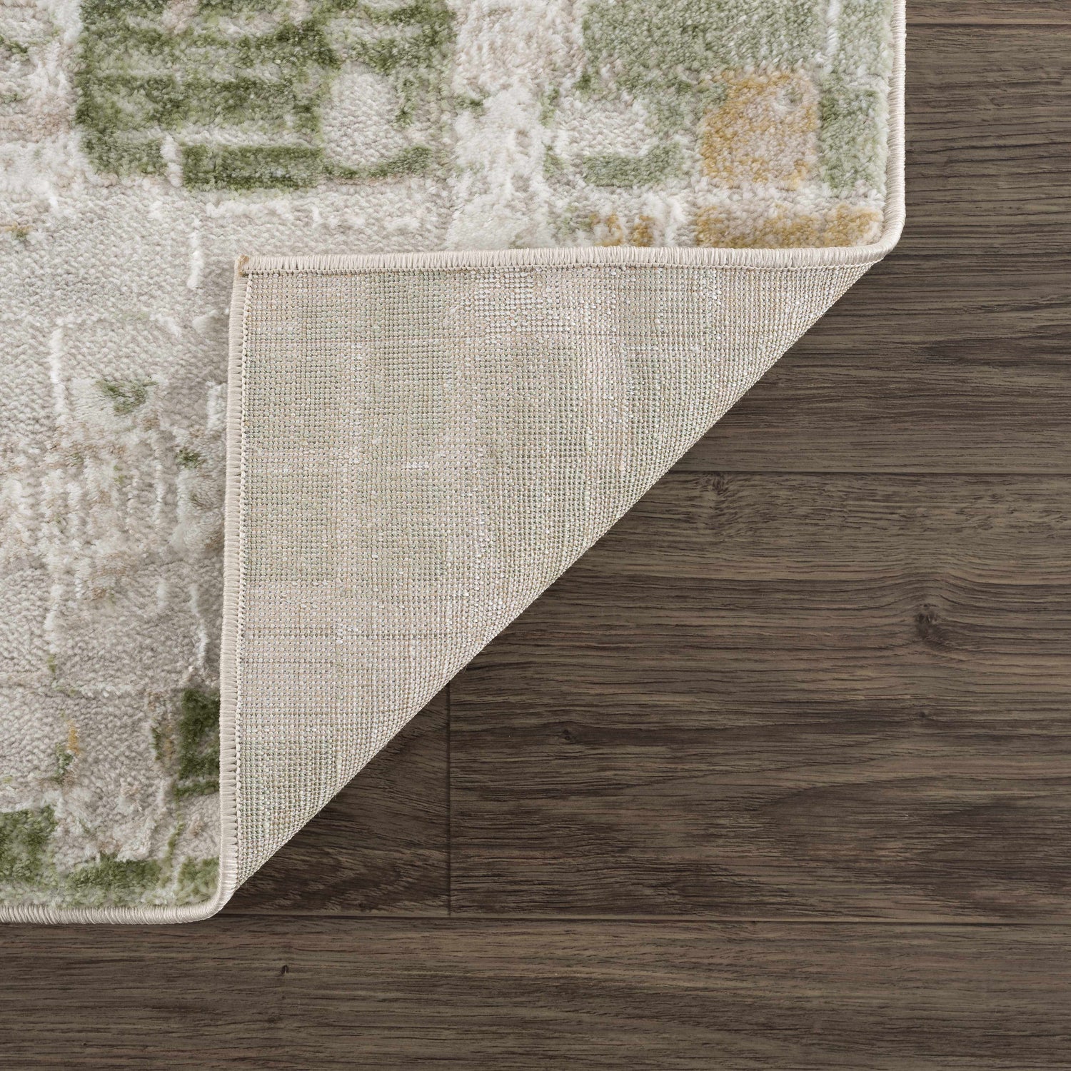 Close-up of the Liveri Green Mosaic Rug showing its abstract pattern, colors, texture, and backing. Fold