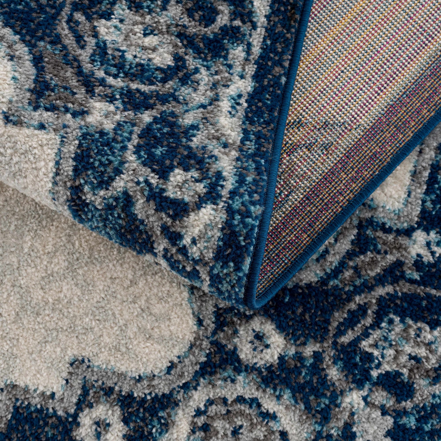 Close-up of the Istanbul Blue Area Rug showing the ivory, navy, and gray vintage-style pattern and woven construction. Fold