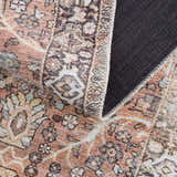 Close-up of the Bian Washable Area Rug showing its Persian-style pattern in peach, beige, and blue tones and its gray backing. Fold