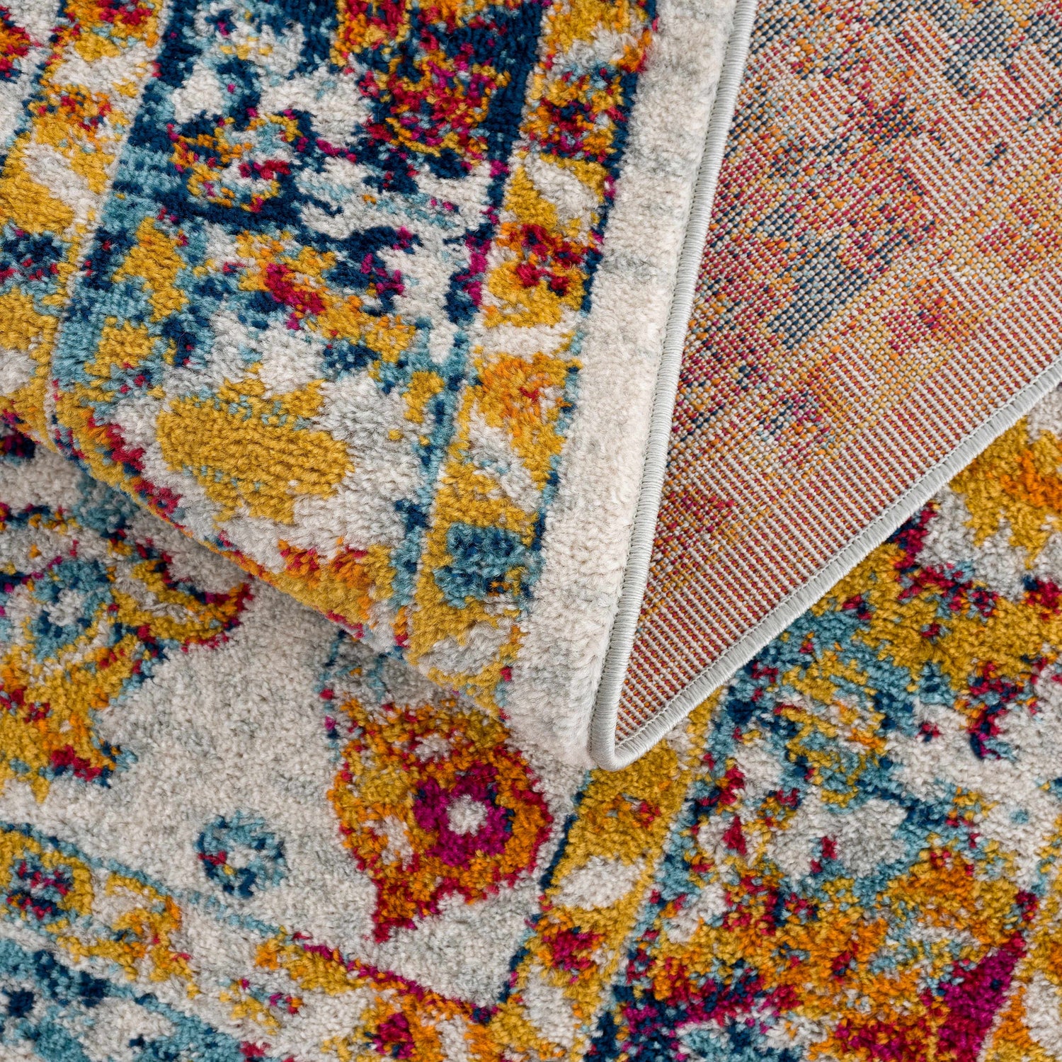 Close-up of the Istanbul Colorful Rug showing its bohemian pattern, light blue, mustard, navy, pink, and off-white hues. Fold