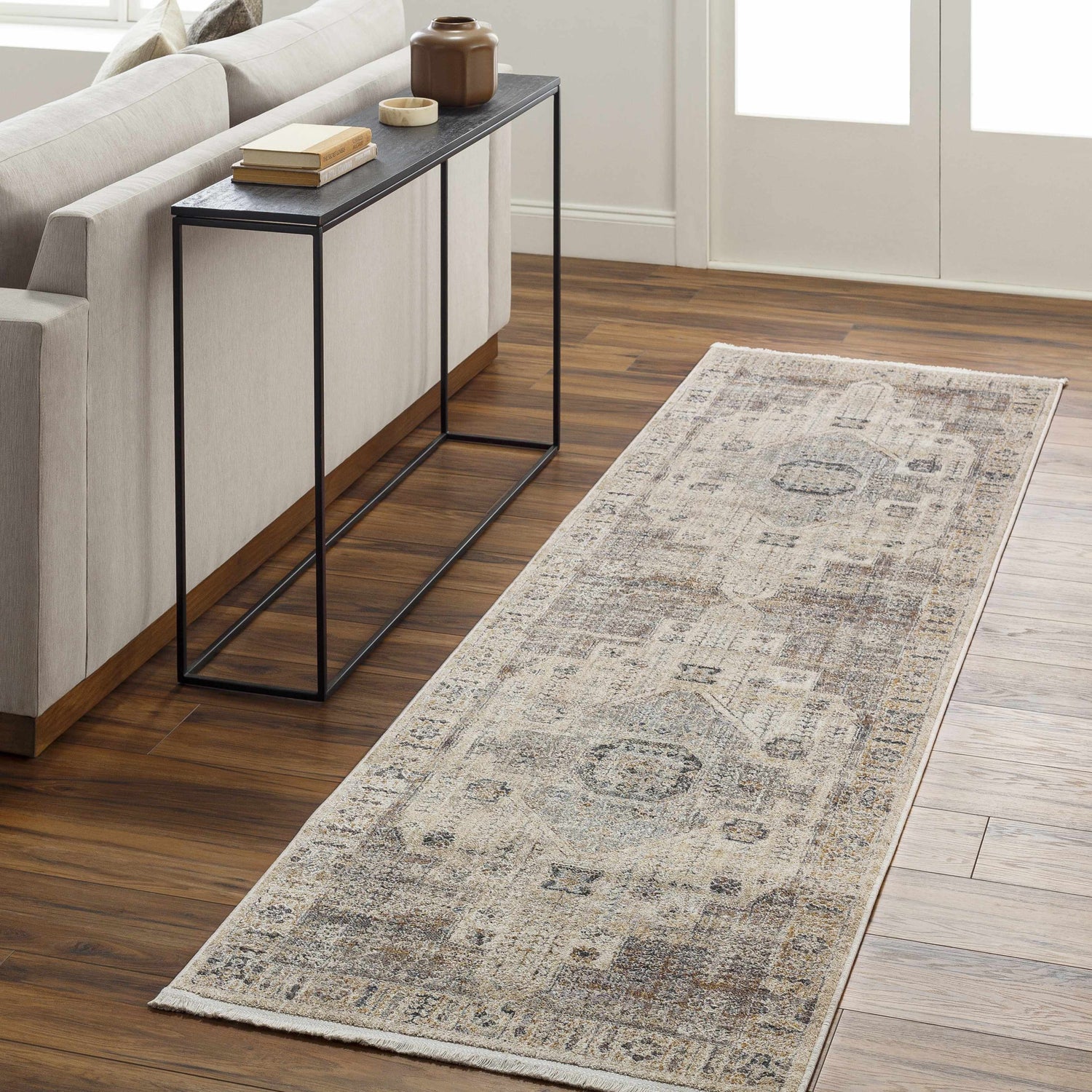 Living room scene with a taupe sofa and the brown and gray Iiona Area Rug runner on hardwood floors. Roomscene-Runner