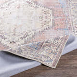 Close-up of the Sacriston Washable Area Rug showing its traditional, bohemian design and colors like aqua, rose, and brown. Fold