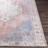 Close-up of the Sacriston Washable Area Rug. Bohemian style rug in aqua, rose, and tan on a dark wood floor. Front