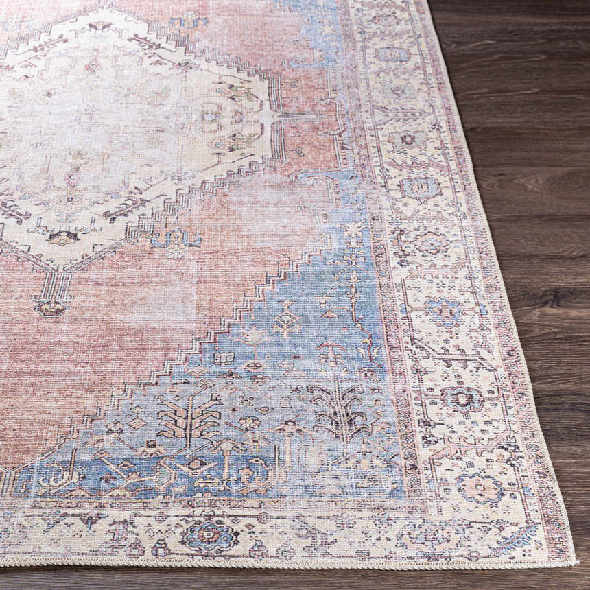 Close-up of the Sacriston Washable Area Rug. Bohemian style rug in aqua, rose, and tan on a dark wood floor. Front