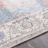 Close-up of the Sacriston Washable Area Rug showing its aqua, blue, and rose bohemian pattern and soft texture. Texture
