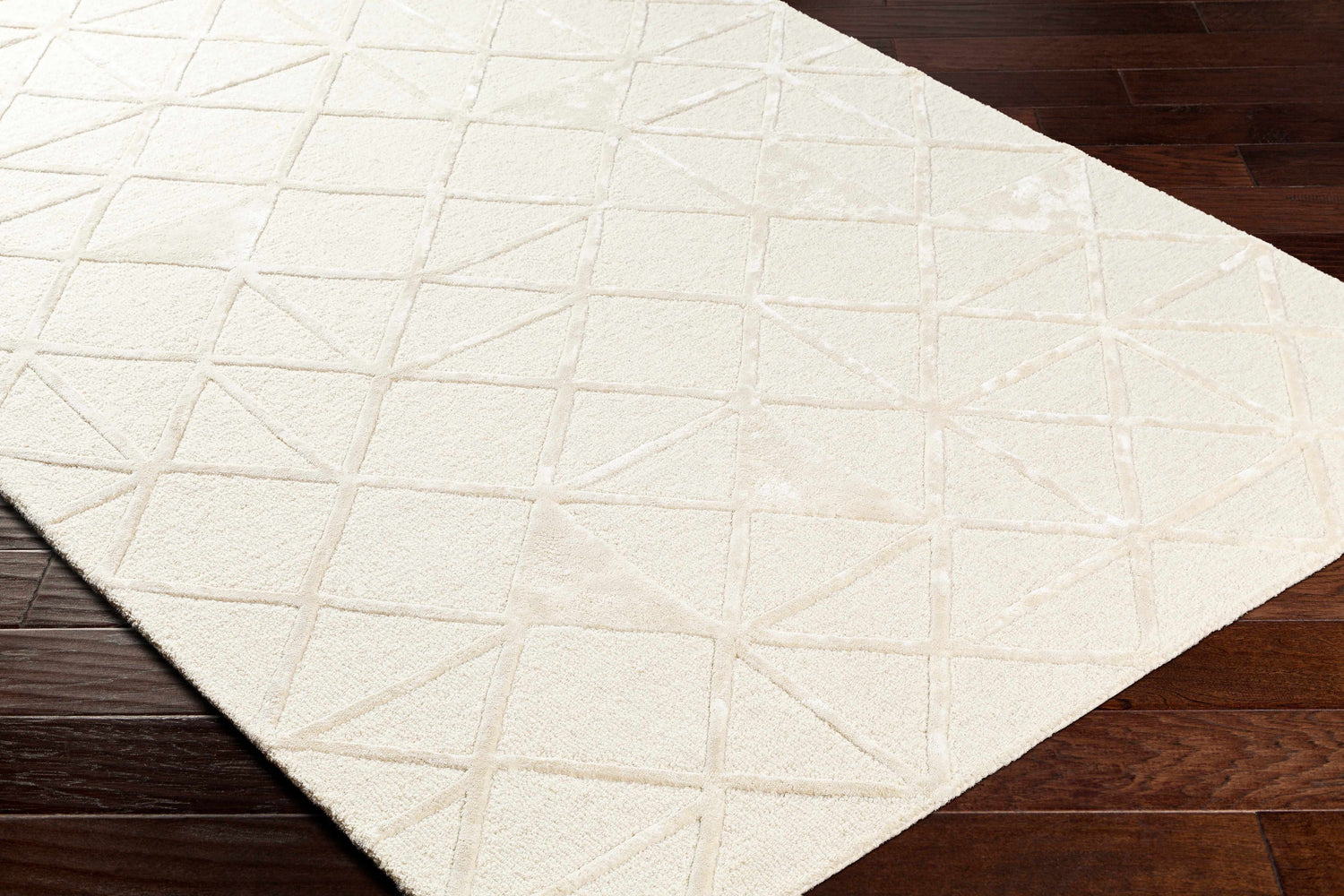 Close-up of the Jevau Beige Geometric rug showing its hand-tufted texture and subtle geometric pattern on dark wood floors. Corner