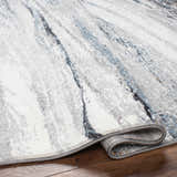 Close-up of the Glain Gray & Blue Marble Area Rug. Features a marble-like pattern in arctic stone, gray, and blue hues. Southwestern style. Fold