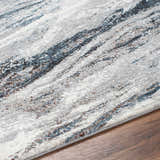 Close-up of the Glain Gray & Blue Marble Area Rug. Features a marble-like pattern in shades of gray, blue, brown, and white. Texture