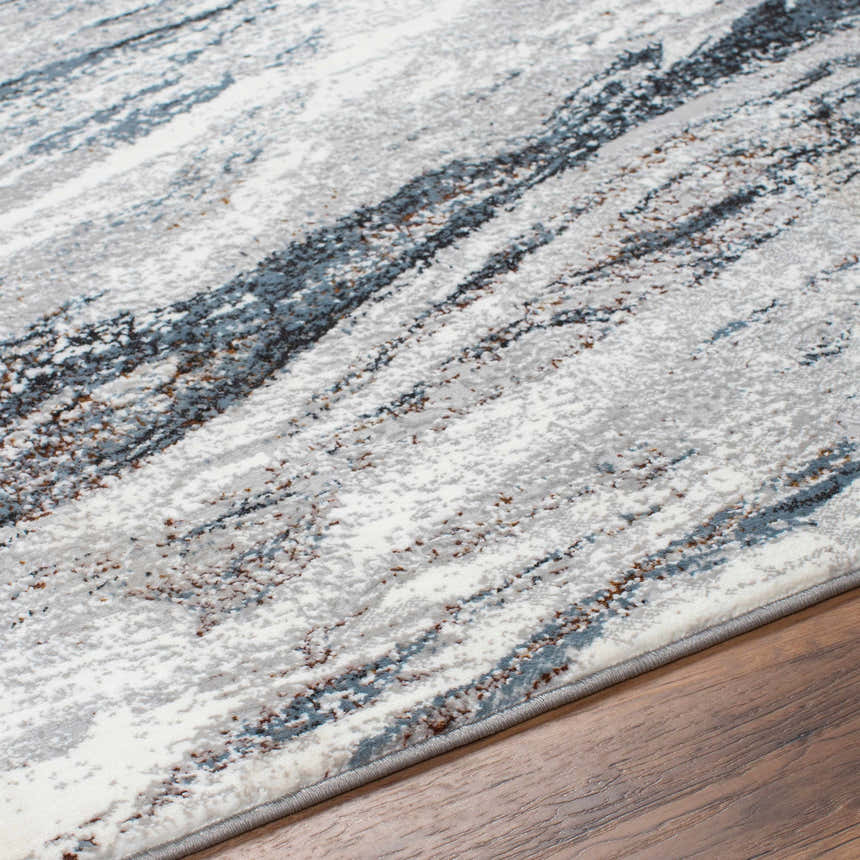 Close-up of the Glain Gray & Blue Marble Area Rug. Features a marble-like pattern in shades of gray, blue, brown, and white. Texture