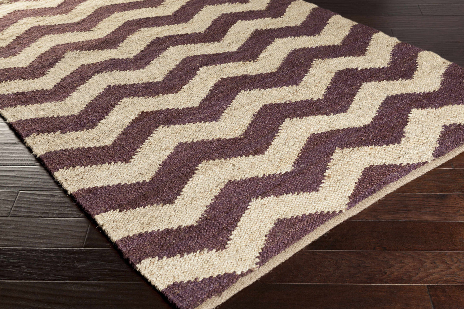 Close-up of the Saginaw Jute Carpet showing a beige and dark purple zig-zag pattern and hand woven texture. Corner