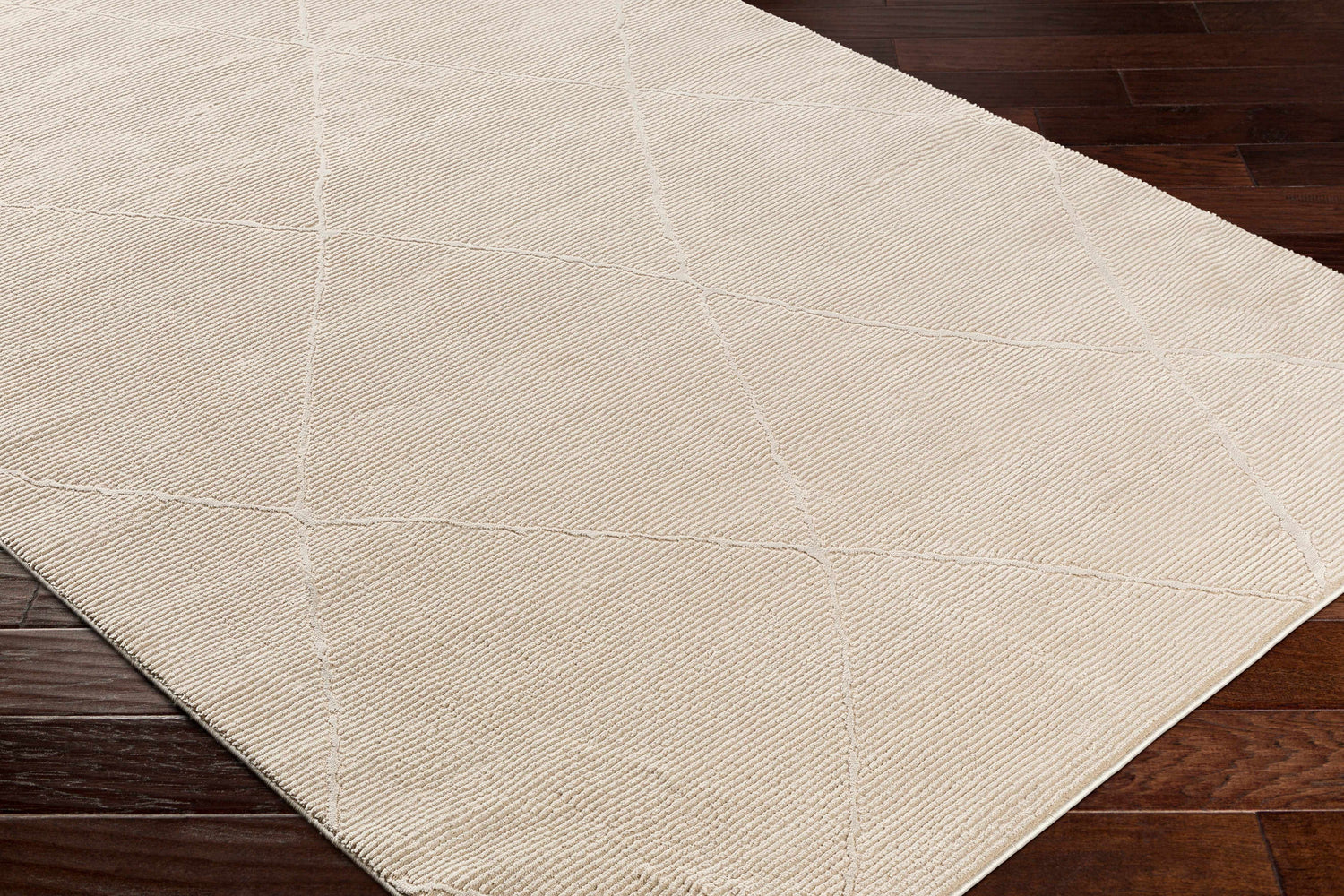 Close-up of the textured Aldis Tan Plush Washable Rug with a geometric pattern on dark wood flooring. Corner