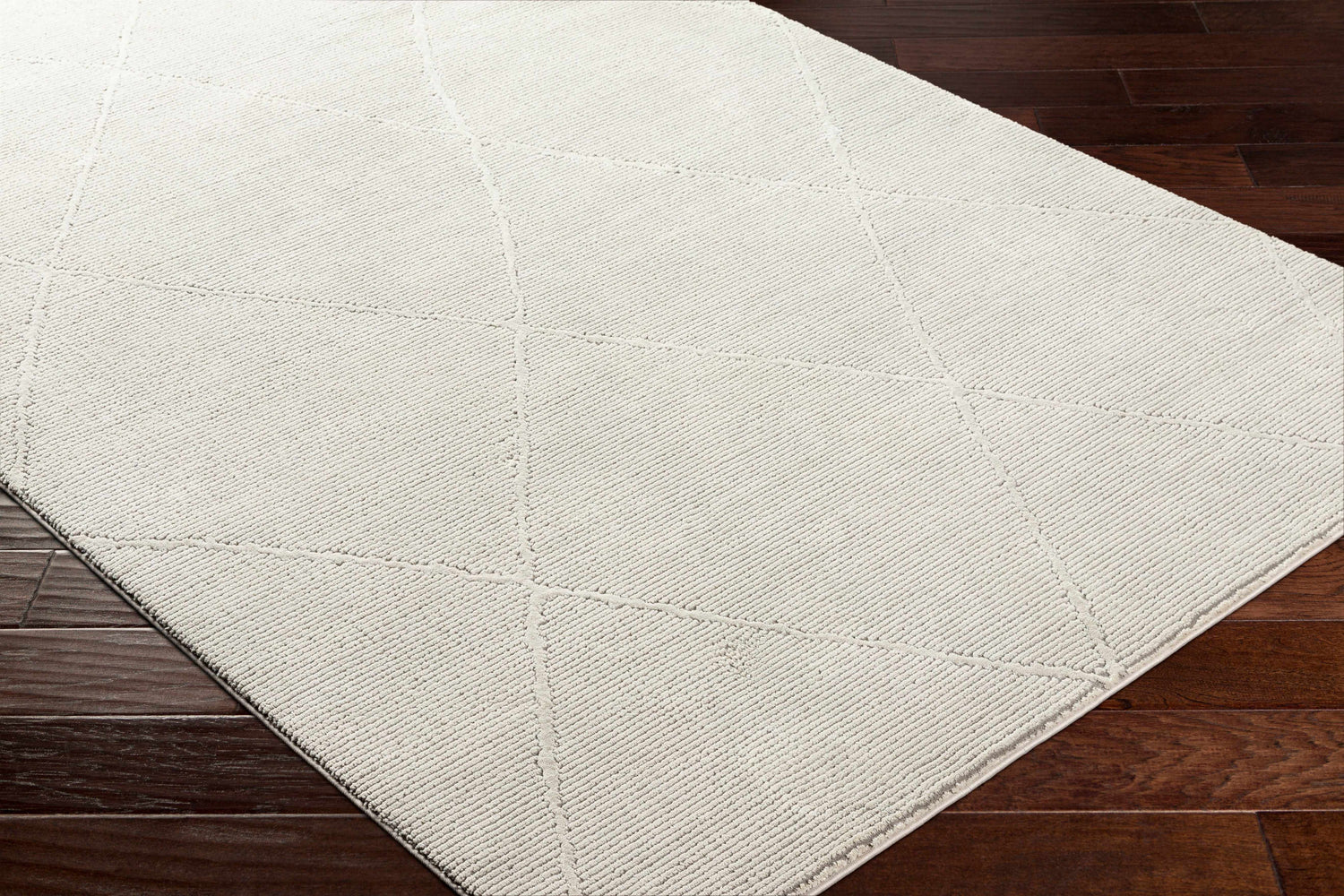 Close-up of the Aldis Grey Plush Textured Washable Rug showing its geometric pattern and soft, plush texture on dark wood floors. Corner
