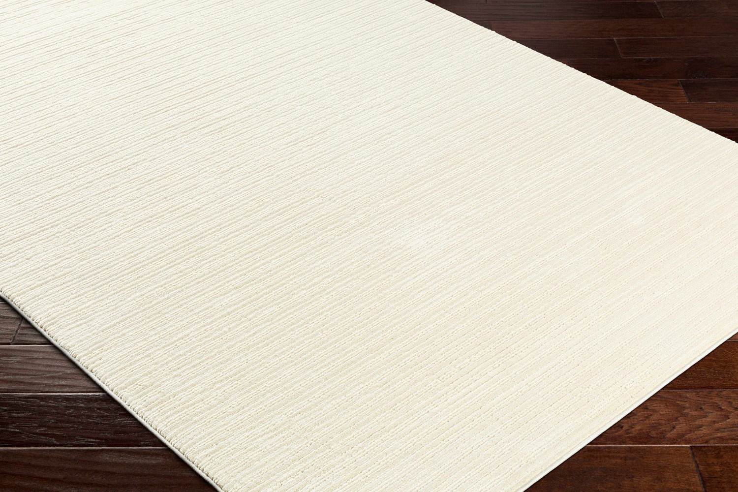 Close-up of a textured Lambswool Kini Plush Washable Rug on dark wood flooring. Corner