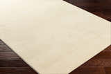 Close-up of a Lambswool Kini Plush Textured Washable Rug showing its plush texture and subtle striped design on dark wood floors. Corner