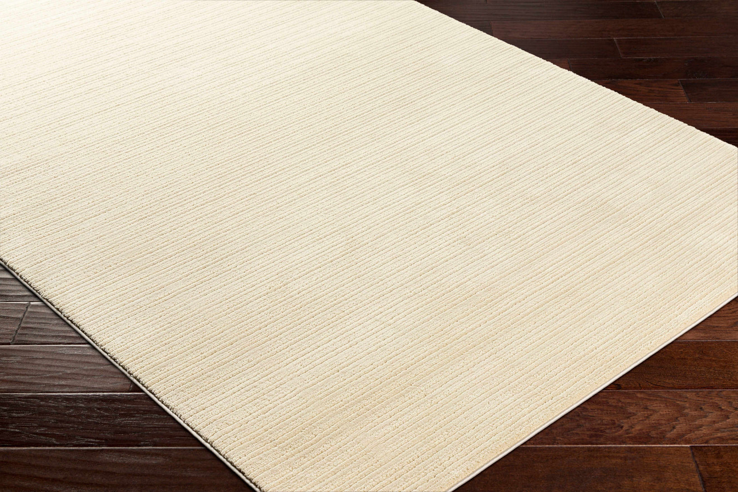 Close-up of a Lambswool Kini Plush Textured Washable Rug showing its plush texture and subtle striped design on dark wood floors. Corner