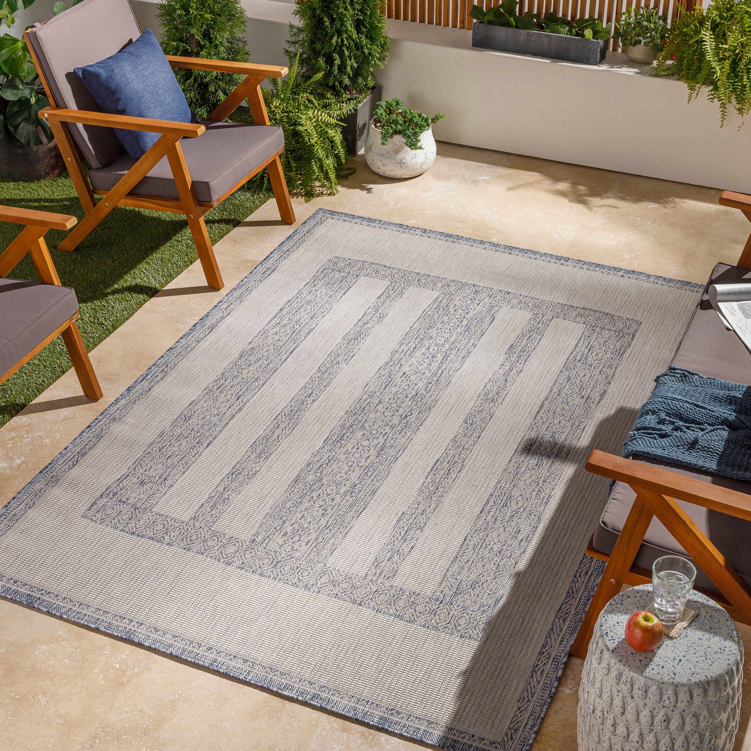 Outdoor patio scene with blue and beige Sallynoggin Indoor & Outdoor Rug, wood chairs, and potted plants. Roomscene-Rectangle